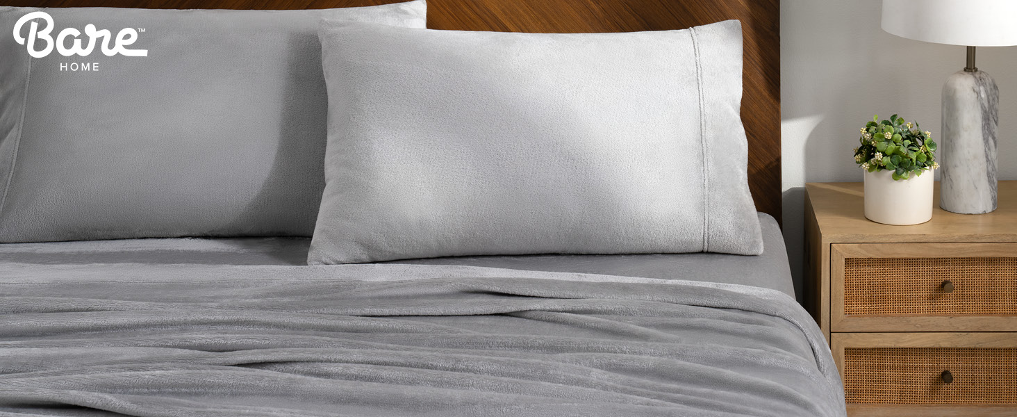 a bedside table next to a bed with microplush sheets on it