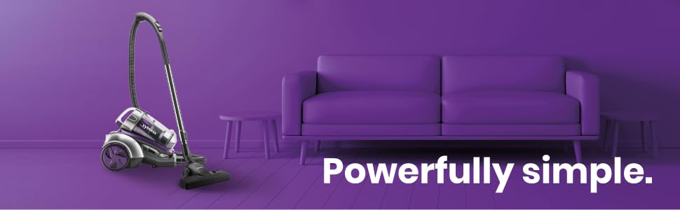 Bagless canister vacuum cleaner next to purple couch in minimalist room. Text 'Powerfully simple.' overlaid.