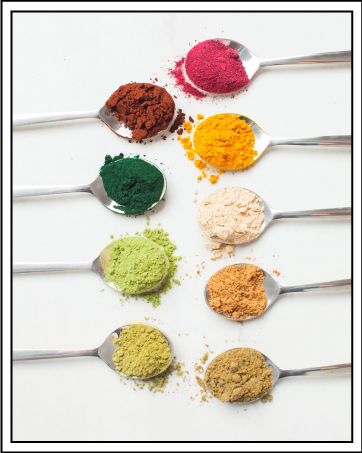 Huit cuillères disposées en rangée, chacune contenant une épice ou un assaisonnement en poudre de couleur différente, y compris des variétés rouges, brunes, jaunes, vertes et blanches