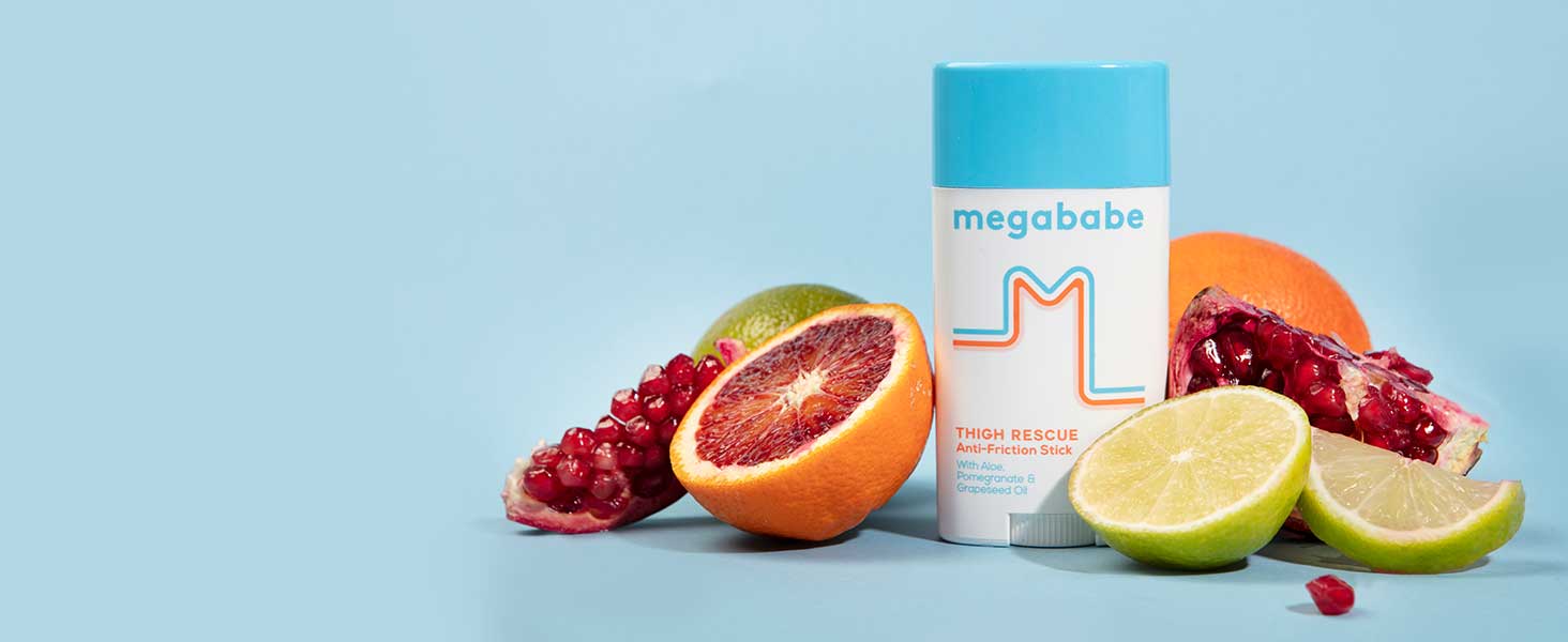 Megababe Thigh Rescue surrounded by oranges, limes and pomegranates. 