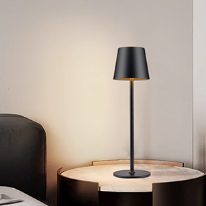 Moderne minimalistische tafellamp met zwarte kap en steel op houten ronde bijzettafel tegen neutrale muur.