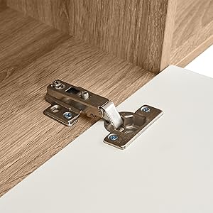 Schrankscharnier aus Metall, das an Holzmöbeln montiert ist und den Mechanismus zeigt, der die Tür mit dem Rahmen in gebürsteter Stahloberfläche verbindet.