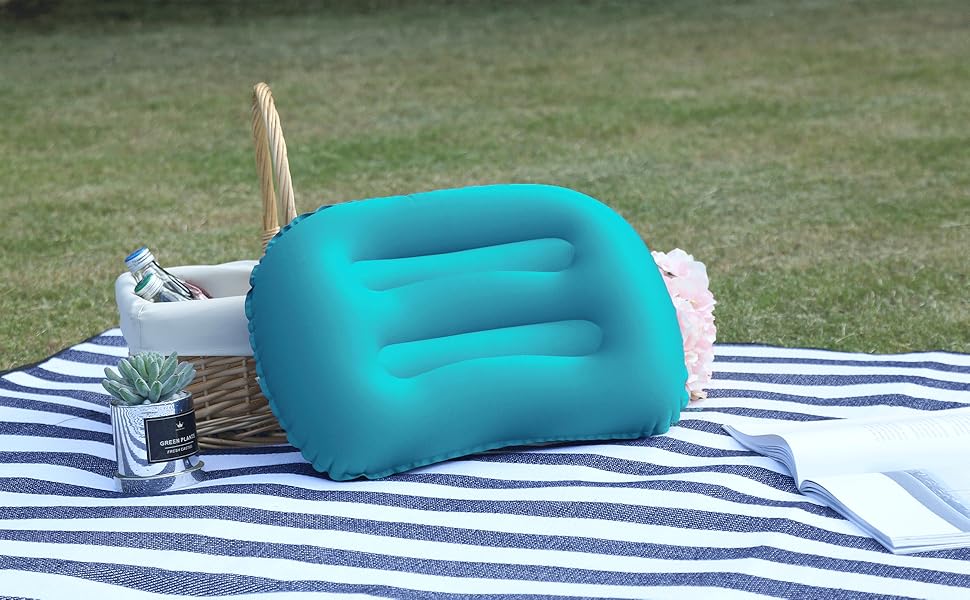 bleu sarcelle sur couverture rayée avec panier en osier. Cadre extérieur sur gazon. L'oreiller a une forme incurvée avec des indentations pour plus de confort et