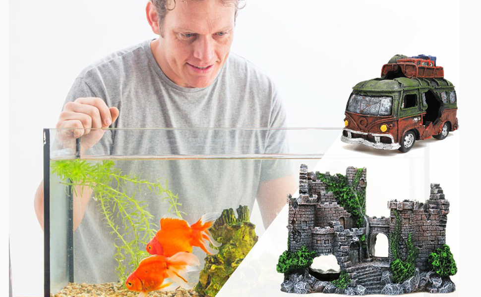 Mann baut Aquarium mit dekorativen Elementen auf, darunter Miniaturburgruinen und einem Spielzeugtransporter im Vintage-Stil darauf.