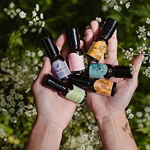 Clarity Blend Aromatherapy Roll On Collection Size Bottles Held In Both Hands In Garden Setting