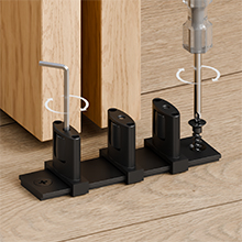 Mehrere Ansichten von schwarzen Türstoppern, die an der Unterseite von Holztüren angebracht werden, zeigen den Installationsprozess und die endgültige Platzierung.