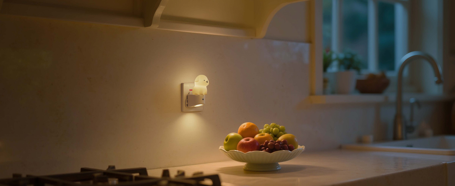 Dimly lit kitchen counter scene with fresh fruit bowl visible, warm ambient lighting from wall sconce.