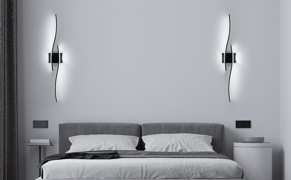 Modern bedroom interior with a gray upholstered bed and two sleek wall sconces. The room features a minimalist design with white walls and bedding.