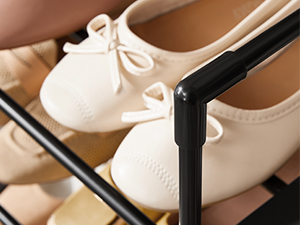 Primer plano de unas zapatillas de ballet de color crema con detalle de lazo, que se muestran en un zapatero u organizador