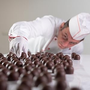 На нескольких снимках изображены руки в белых перчатках, которые держат и раскладывают на светлой поверхности нечто, похожее на шоколадные кондитерские изделия.