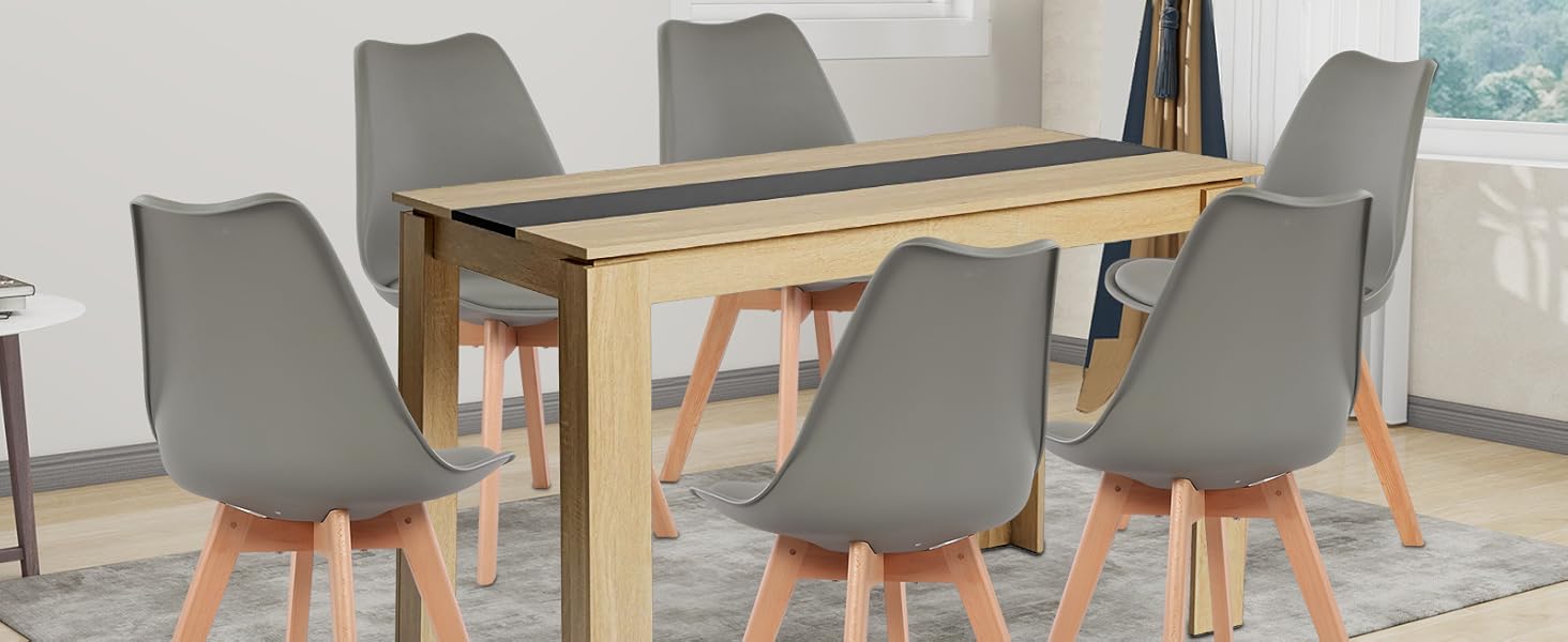 Essgruppe mit Holztisch mit dunkler Intarsie und sechs grau geformten Stühlen mit Holzbeinen. Tisch auf grauem Teppich in hellem Raum mit Fenster und Kunstwerken