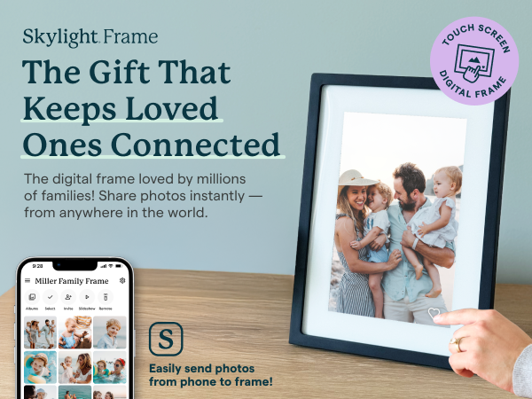 Skylight digital photo frame on table, with hand holding phone.