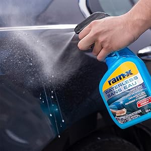 man holding bottle of Rain-X Waterless Wash & Wax and spraying onto black car