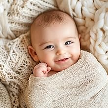 a beautiful baby smiling on a blanket sitting on soft blankets