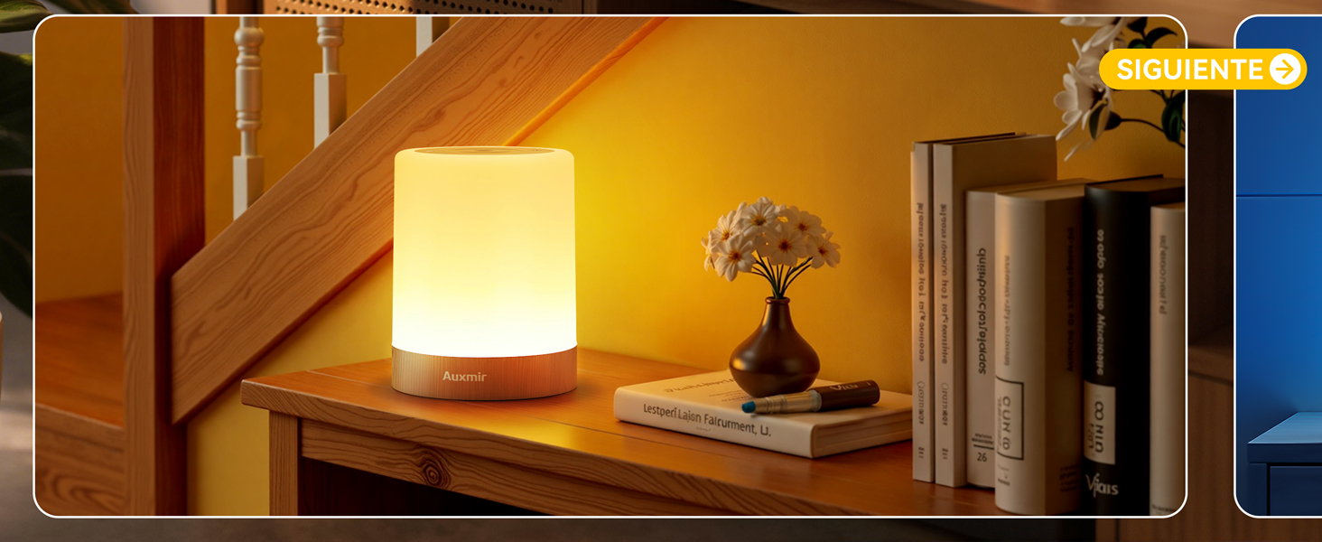 con pantalla blanca que emite luz cálida, colocada sobre una superficie de madera junto a libros y plantas pequeñas, creando un ambiente acogedor contra una pared amarilla
