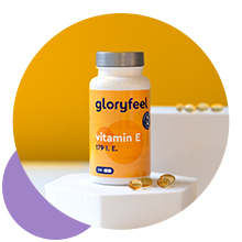 Bouteille orange de suppléments vitaminiques étiquetée « gloryfeel » sur fond jaune avec un bol blanc contenant des capsules au premier