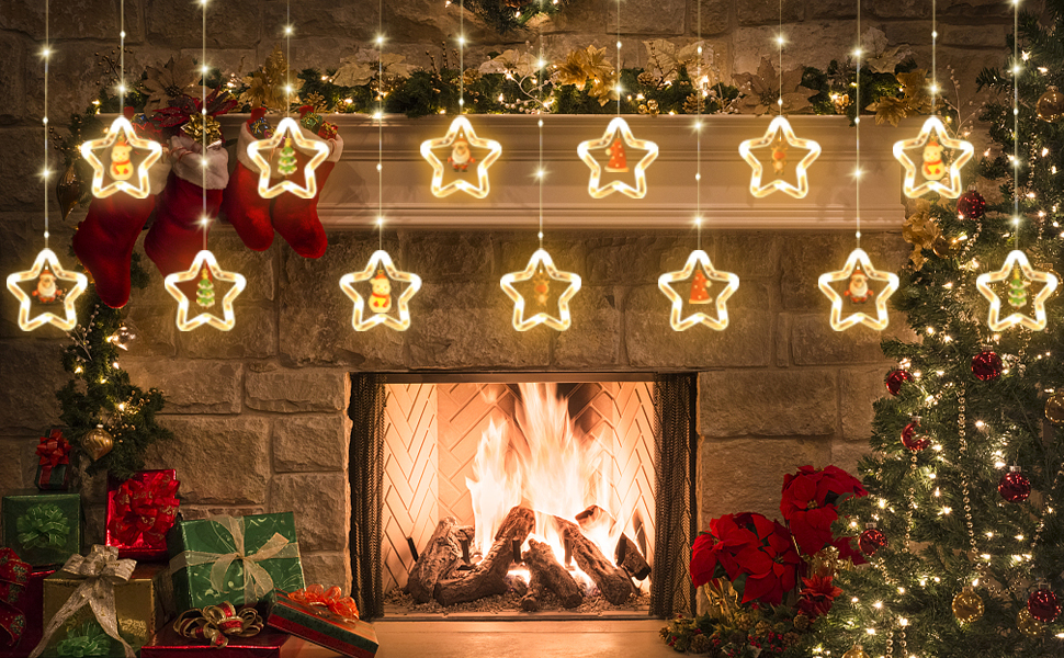 Festive fireplace with lit fire, decorated with hanging star-shaped string lights, garland, and red stockings. Christmas tree visible to the side.