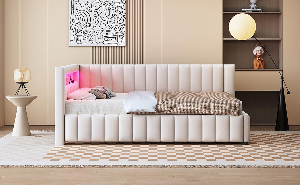Modernes Schlafzimmerinterieur mit weiß gepolstertem Tagesbett, pinkfarbenen Akzentkissen, abstrakter Wandkunst und hölzernem Beistelltisch mit sphärischer Lampe