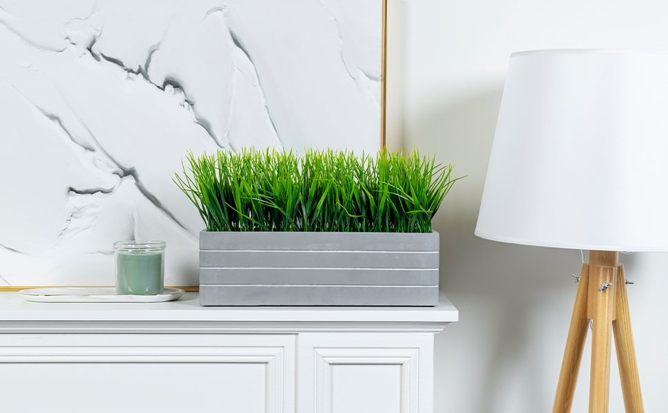 faux grass plant potted in cement planter displayed on mantel