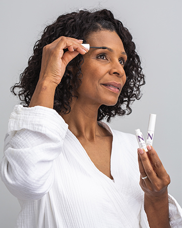 Woman putting Nulastin BROW serum on her eyebrows