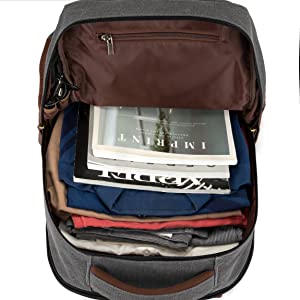 Sac à dos ouvert contenant des vêtements, des magazines et des articles de voyage soigneusement emballés. Extérieur gris avec compartiment supérieur marron.