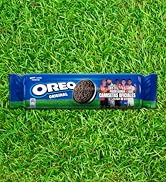 El texto dice «OREO». Paquete de galletas Oreo azul fotografiado sobre un fondo de hierba verde brillante.