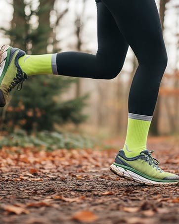 SPIRESNUG runner in neon green socks on leafy trail. Dynamic motion.