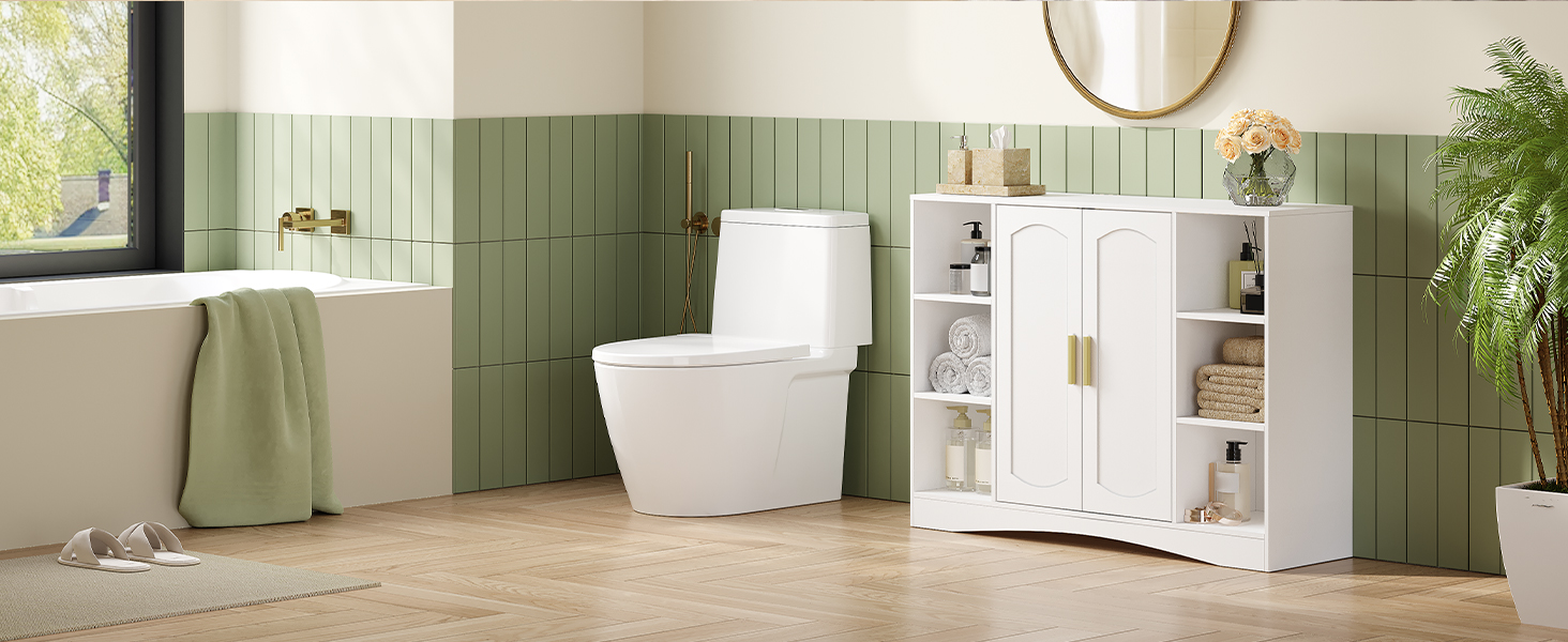 Modernes Badezimmer mit weißer Toilette und Stauraum vor einer grün gefliesten Wand. Holzboden, runder Spiegel und sichtbare Zierpflanzen. Natürliches Licht aus dem Fenster.