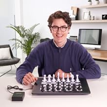 un homme assis à un bureau avec un échiquier et un écran d'ordinateur.