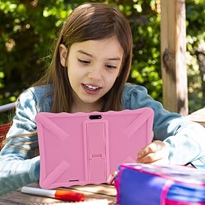 a young girl sitting at a table with a pink tablet.