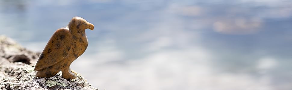 Soapstone eagle sculpture on rock by ocean