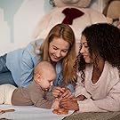 Two moms cuddling their newborn baby together, smiling and filled with joy