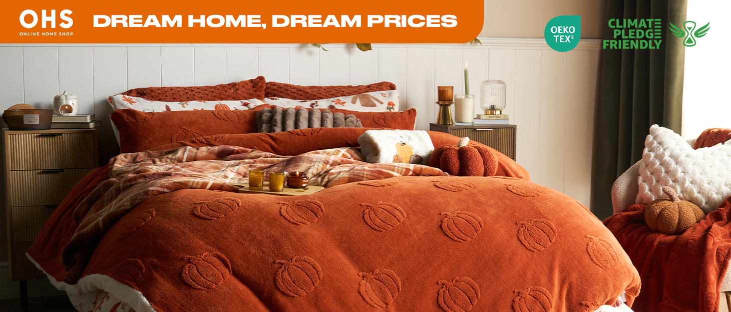 Text reads 'ONE DREAM HOME DREAM BIGGER'. Luxurious bedroom setting with burnt orange bedding and multiple decorative pillows on a well-made bed.
