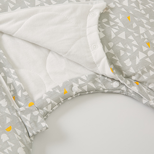 Close-up of white textured fabric with delicate floral pattern and subtle metallic gold accents against light background.