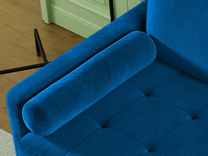 Close-up of a blue velvet or plush upholstered piece of furniture featuring detailed button upholstery and a rolled arm or backrest