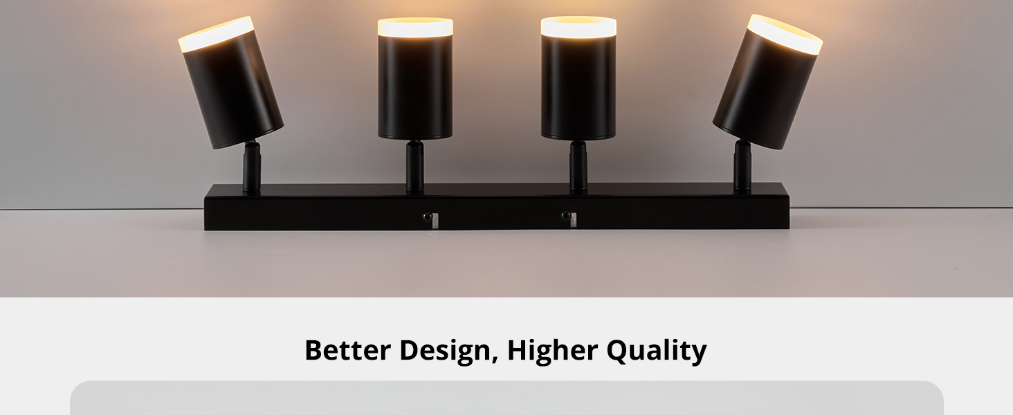 Modern track lighting fixture with four black cylindrical spotlights mounted on a linear bar, illuminated against a neutral background.