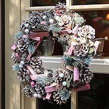 a wreath with pine cones and a pink ribbon