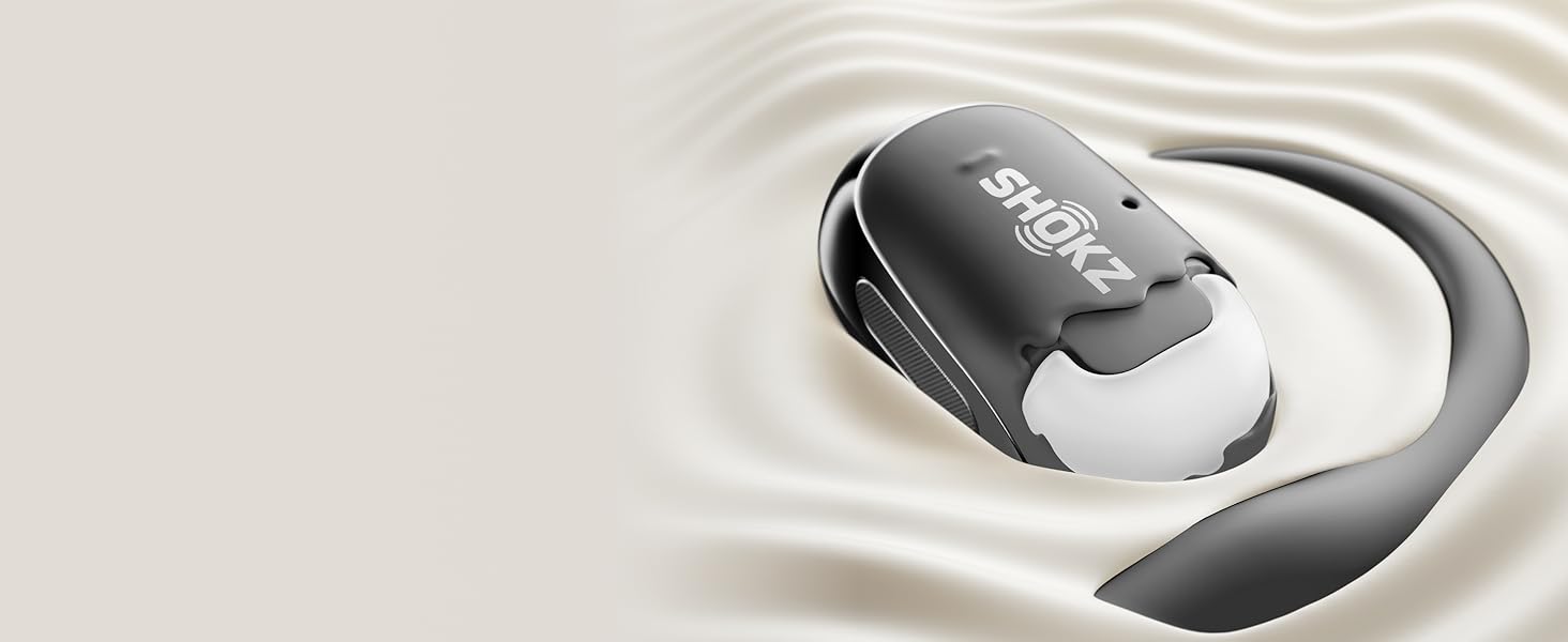Écouteur ou appareil auditif sans fil gris et blanc flottant sur une surface blanche ondulée, avec la marque « Shokz » visible