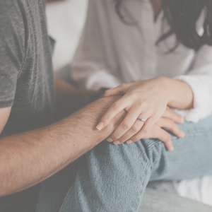 Two people with their hands holding each other on their lap