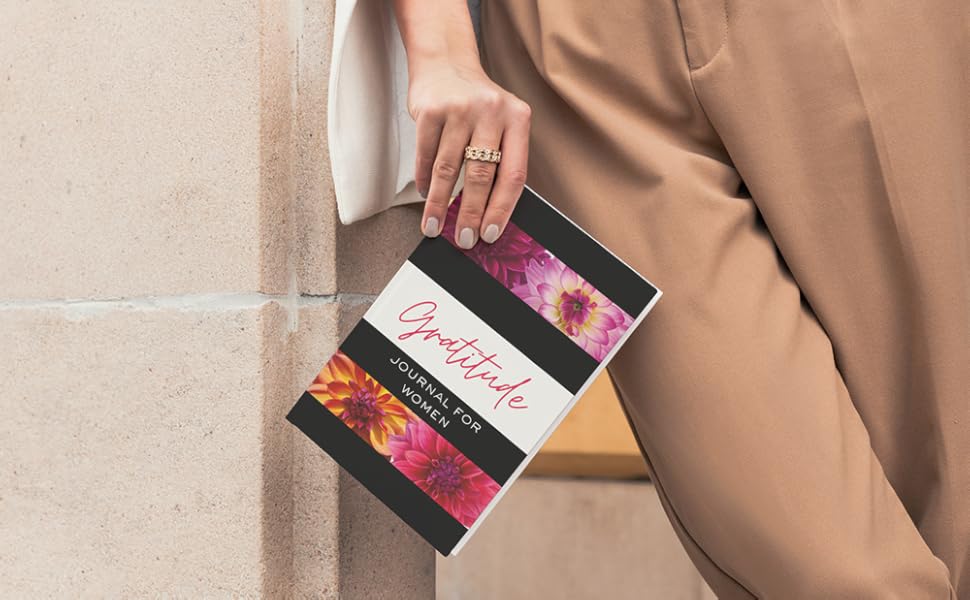Woman leaning against wall holding a gratitude journal