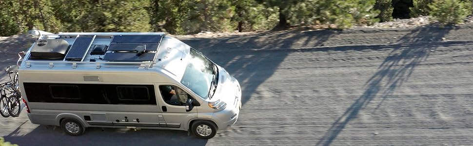 Winnebago Travato driving down a mountain road with Zamp Solar obsidian solar panels mounted on top