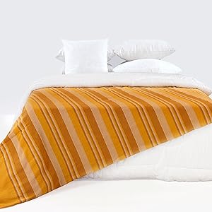 Gelber Überwurf auf dem Bett.