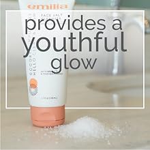 Full frontal shot of face wash bottle next to a small pile of salt on stone bathroom counter