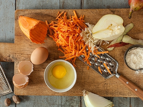 Grated sweet potato and apple on wooden cutting board.