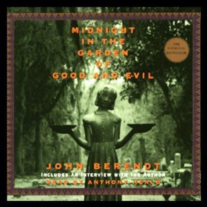 A stone statue of a small girl holding bowls in her hands, it is in a graveyard and has lots of trees in the background. 